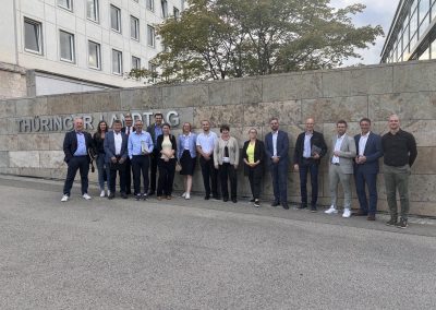 Gruppe vor einer Steinwand mit dem Schriftzug „Thüringer Landtag“.